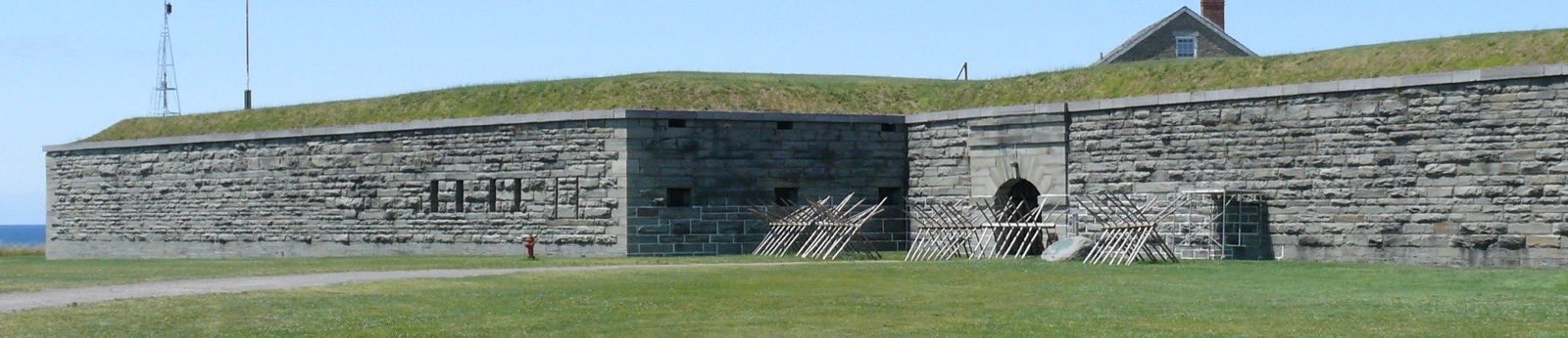 The stone ramparts and earth glacis of Fort Ontario above Oswego harbour, with Lake Ontario on the horizon