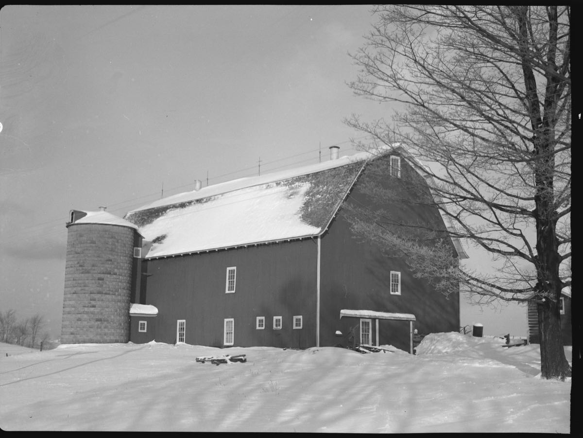 A gambrel-roofed dairy barn and concrete stave silo under snow on William Wallace's farm near Pulaski, photographed in December 1937